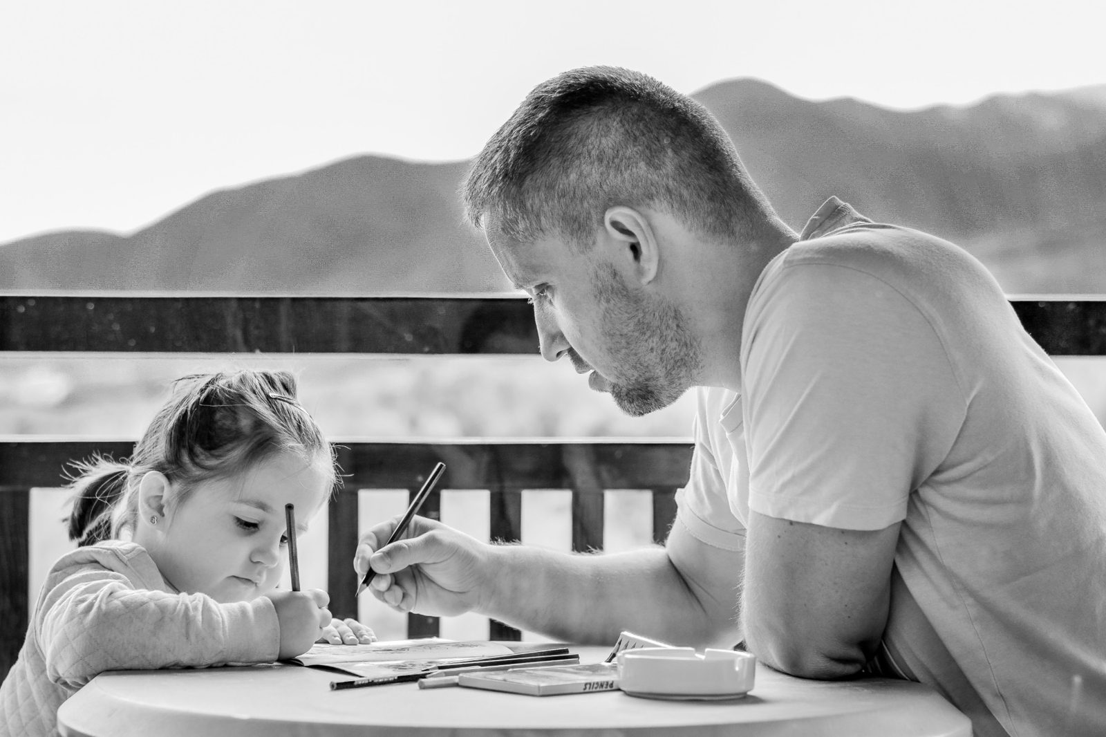 Ein Vater und seine kleine Tochter malen gemeinsam am Tisch.